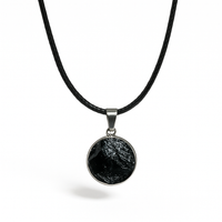 Colgante circular de turmalina negra con cordón negro sobre fondo blanco. Fotografía de joya protectora de Yo Soy Munduko.