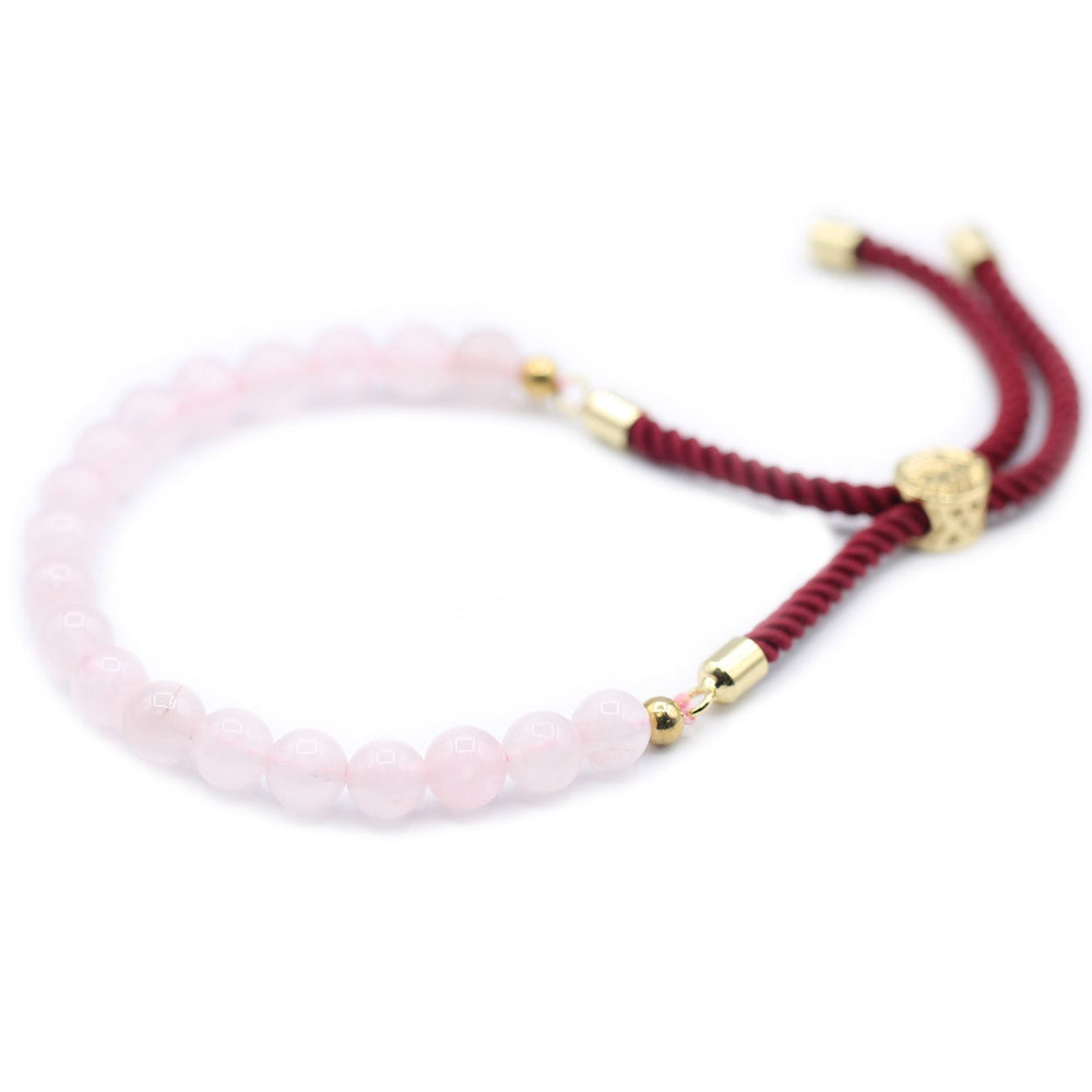 Pulsera ajustable de hilo rojo con cuarzo rosa, imagen enfocada en el diseño y su simbolismo protector.
