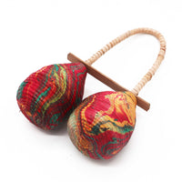 Sonajero Maracas Doble Lazo: dos cabezas en lágrima, fibras vegetales y colores rojo, verde y amarillo; asa de tela - ritmo.