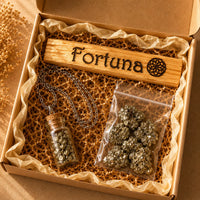 Colgante de frasco con pirita y palo santo grabado con “Fortuna”, sobre base beige de travertino. Imagen espiritual de productos energéticos Yo Soy Munduko.