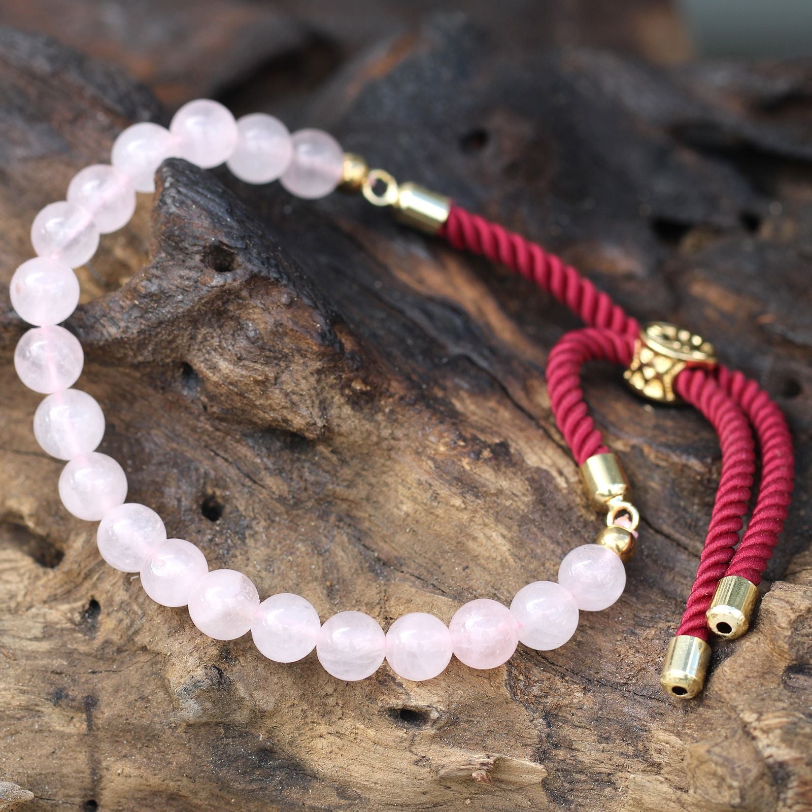 Pulsera energética con hilo rojo y cuarzo rosa, fotografía de producto con detalle de la piedra pulida