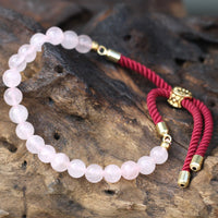 Pulsera energética con hilo rojo y cuarzo rosa, fotografía de producto con detalle de la piedra pulida