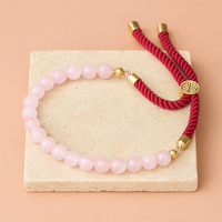 Pulsera de hilo rojo con cuarzo rosa natural sobre fondo corporativo joya energética para protección y amor.