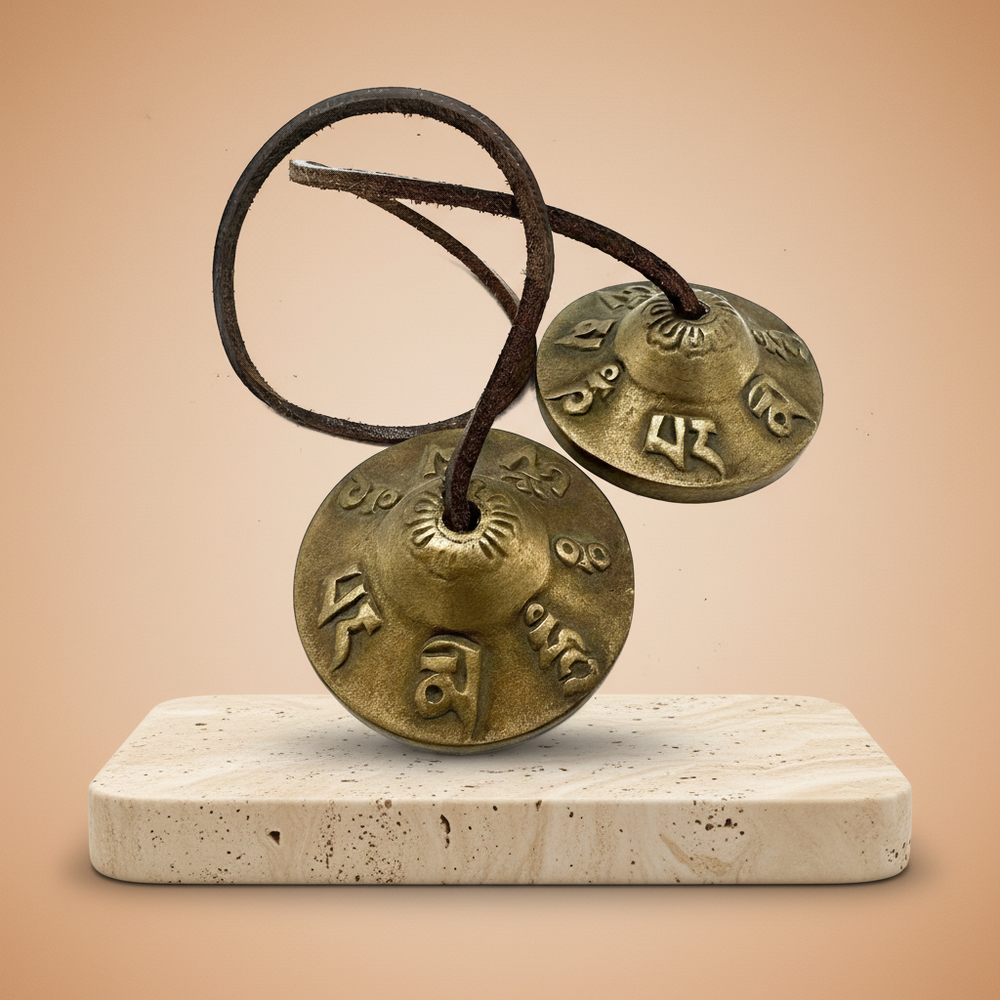 Tingsha tibetana: címbalos de bronce 6 cm con cuero; símbolos de suerte grabados; sonido claro para purificación y relajación.