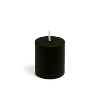 Vela negra cilíndrica sobre fondo beige espiritual, símbolo de limpieza energética y protección. Imagen de producto esotérico Yo Soy Munduko.